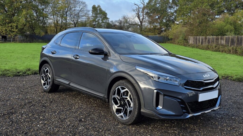 Grey KIA car with grass and trees in the background - a car available for hire in Hertfordshire