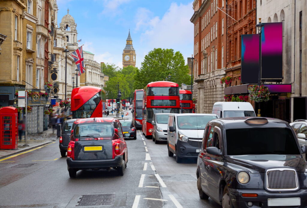 Image of heavy traffic in central London with black taxies and red buses with Big Ben in the background